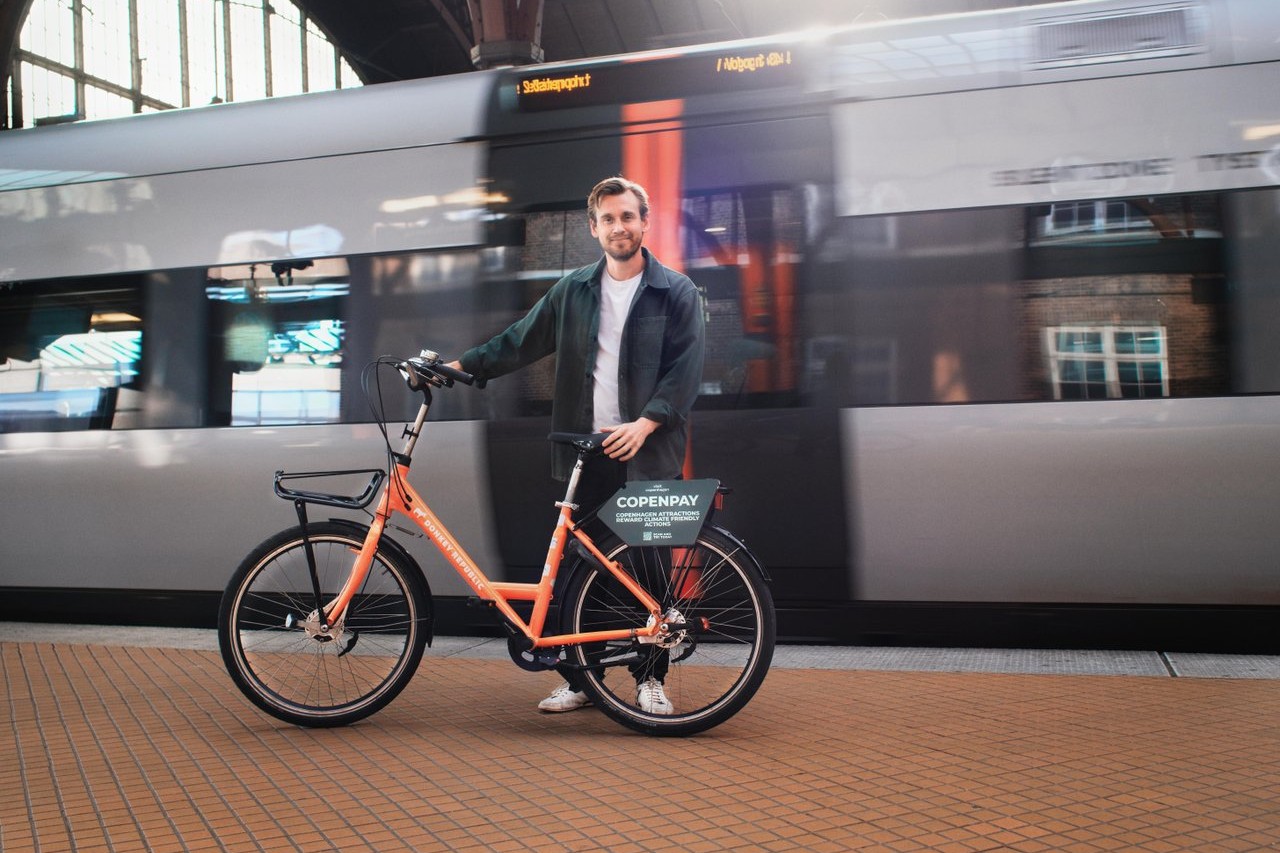 Man standing at a train station with a bike