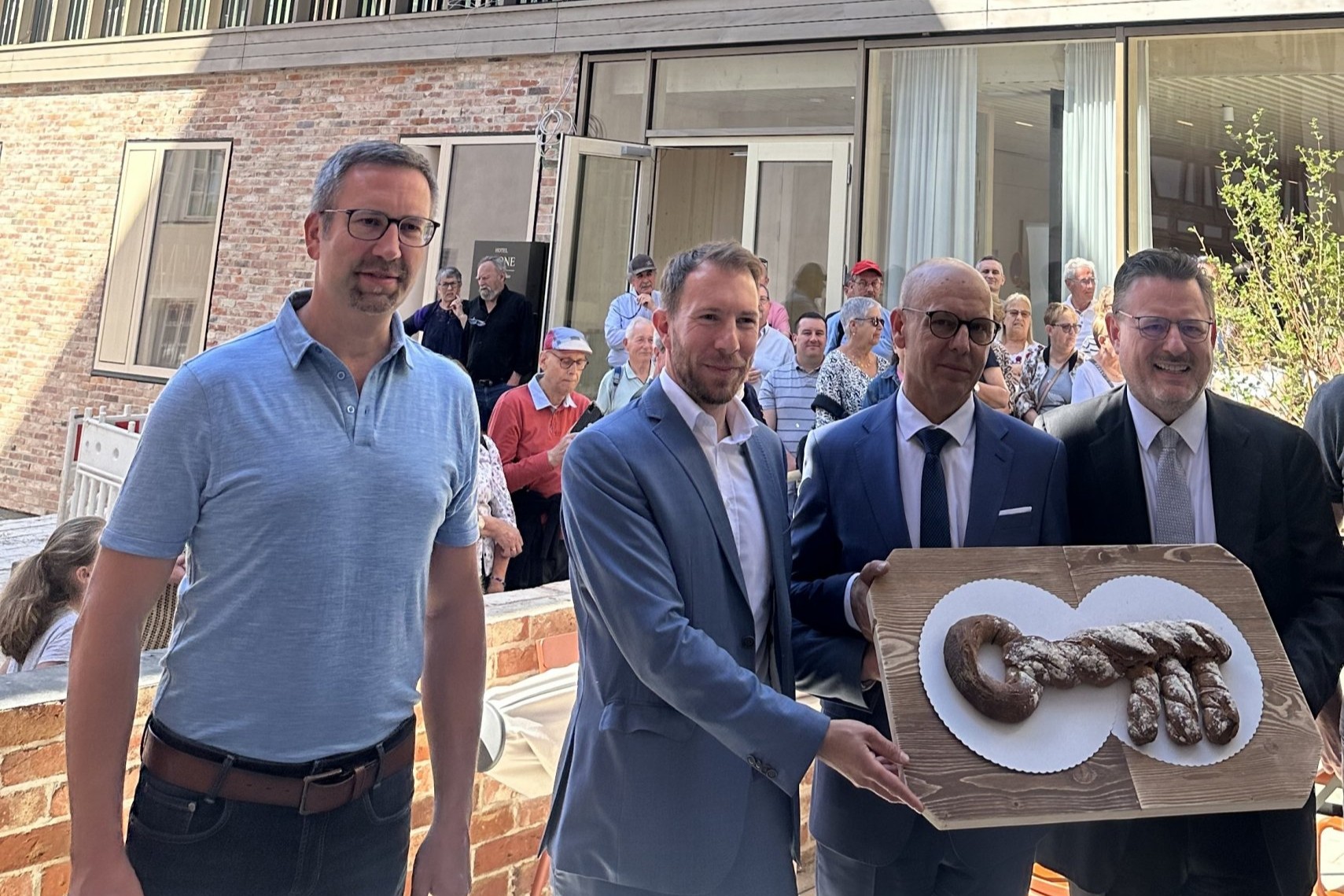 4 Männer, 3 halten ein großes Brot in Form eines Schlüssels hoch