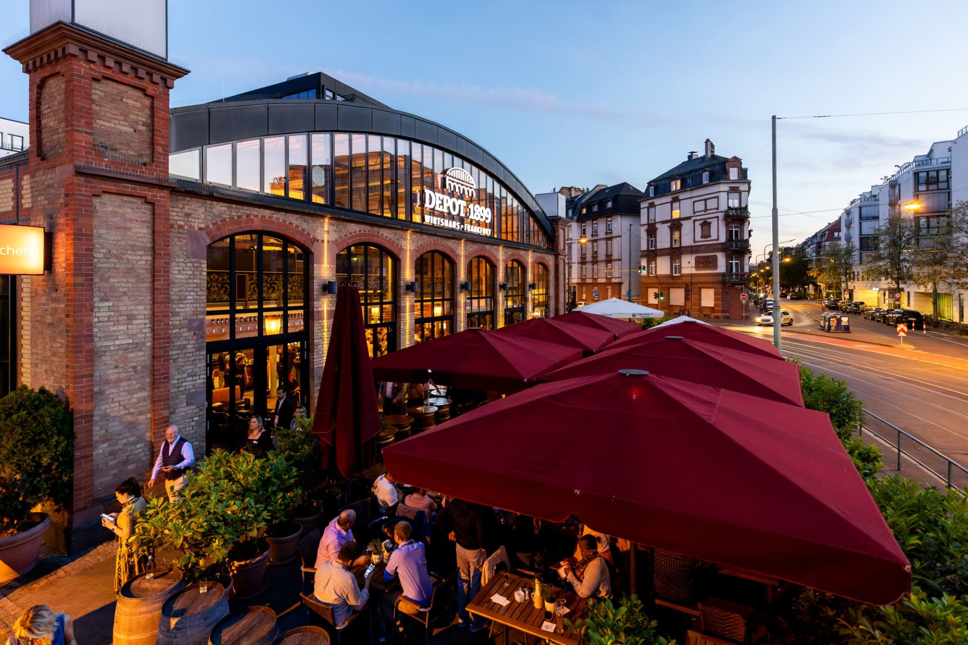 People dining outside in the evening under large umbrellas