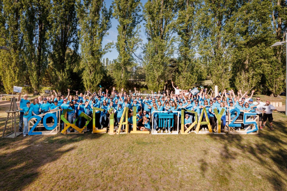 Eine Gruppe Menschen in blauen Shirts auf einer Wiese, die in die Kamera lächeln