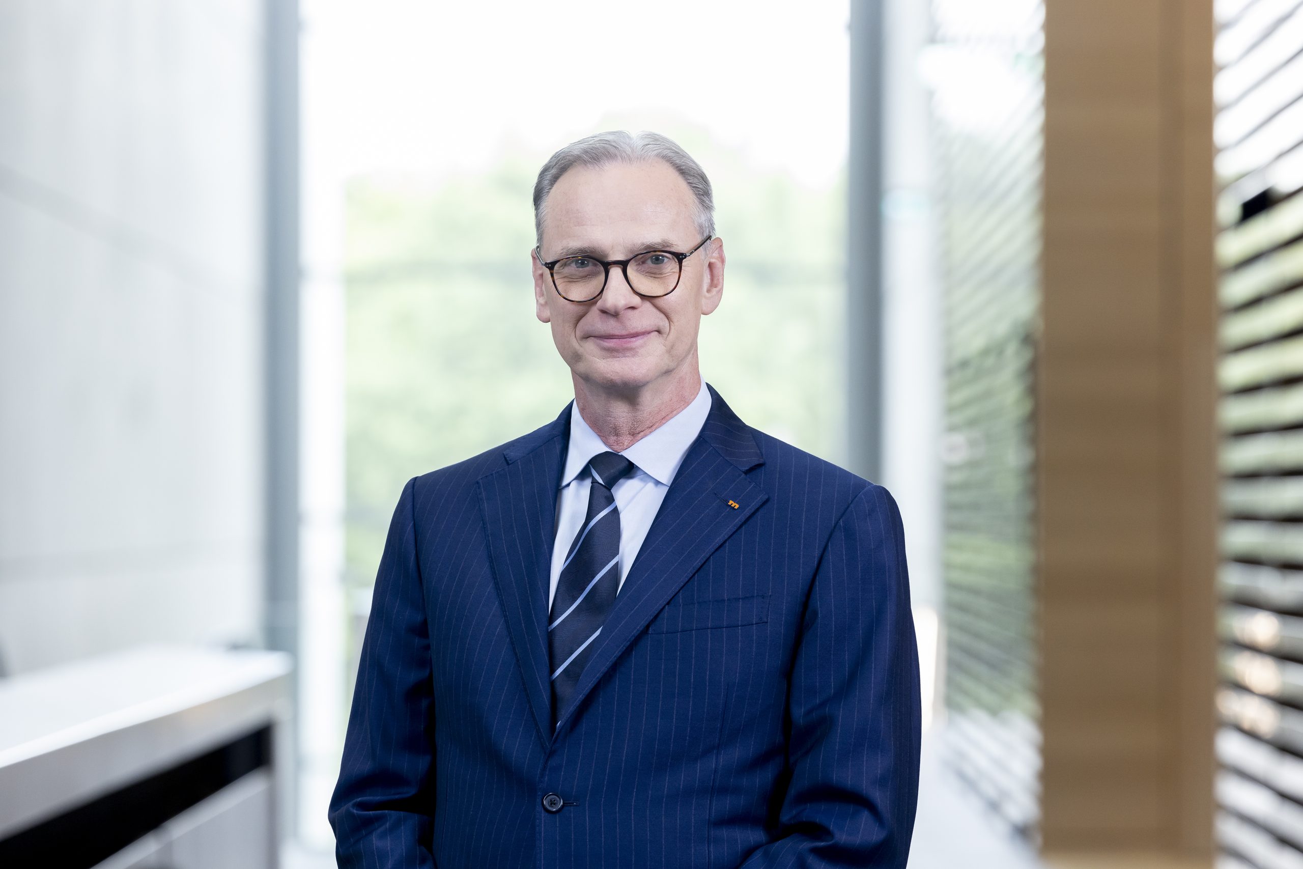 Mann in blauem Anzug und mit Brille schaut in Kamera
