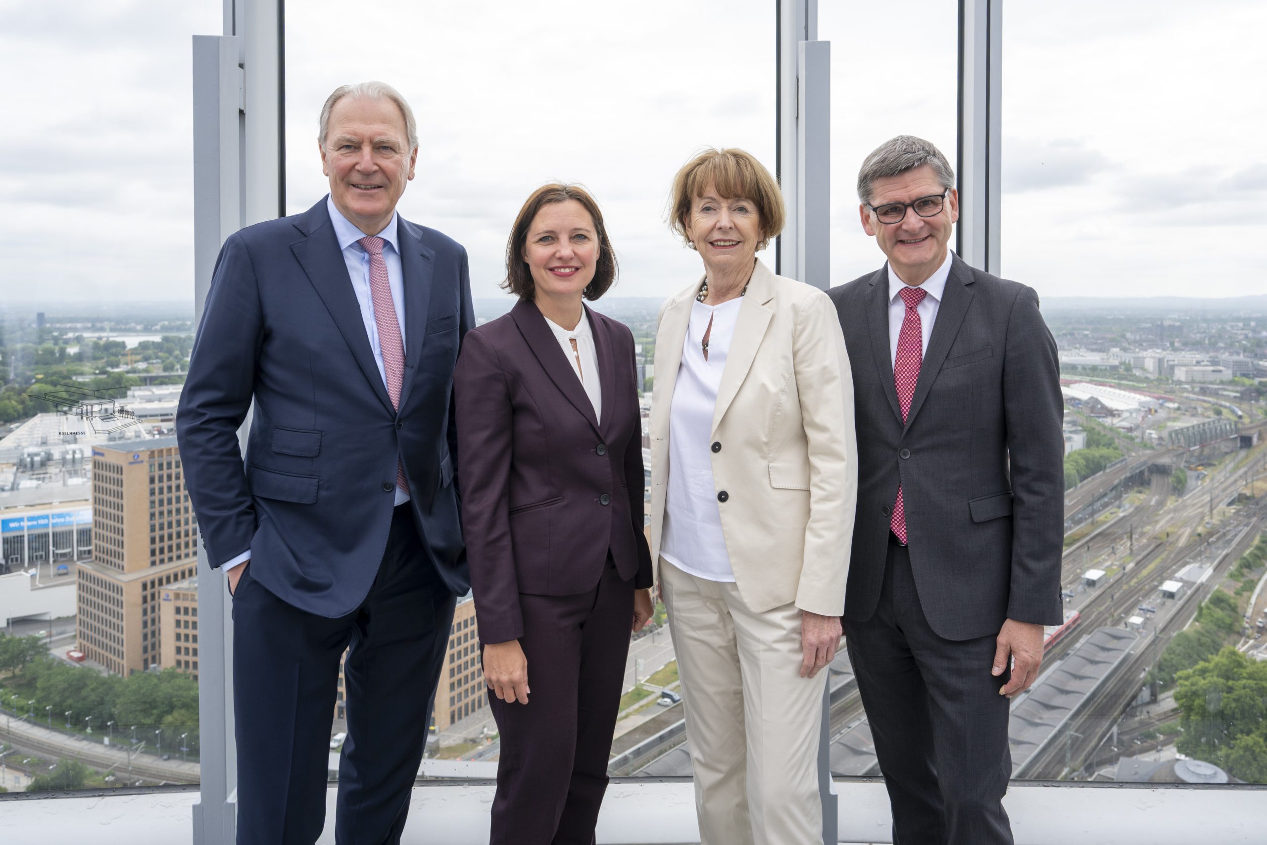 Zwei Frauen und zwei Männer in Business Kleidung schauen in die Kamera