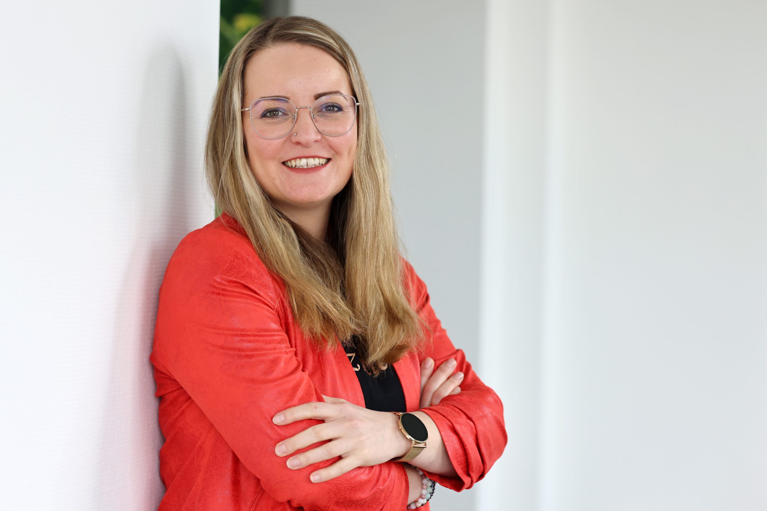 Frau in rotem Blazer und mit verschränkten Armen