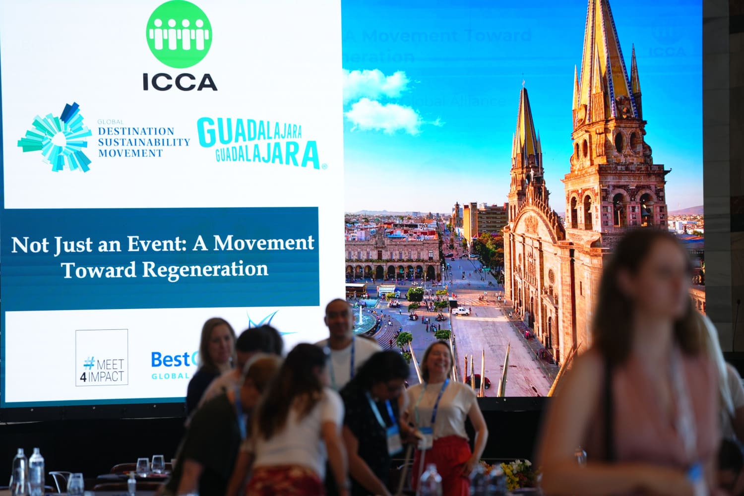 People in front of a stage with a ICCA presentation